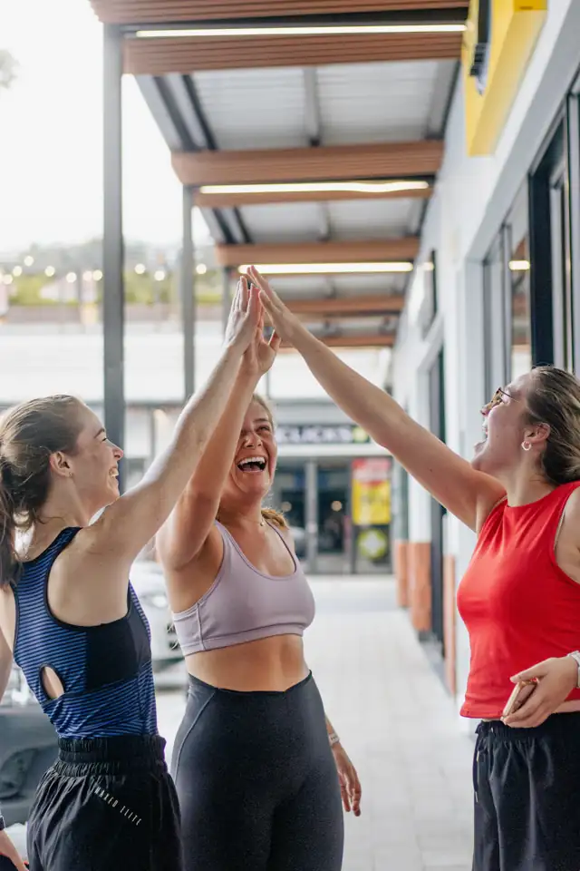 Três amigas comemorando com um high five depois de treinar