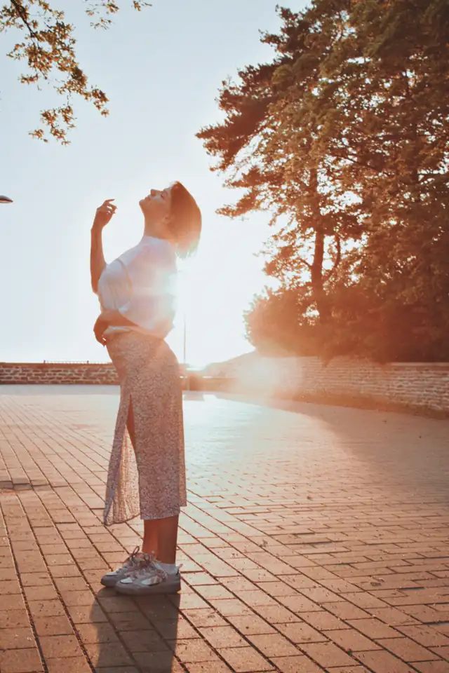 Mulher se alongando ao sol em uma calçada de tijolos