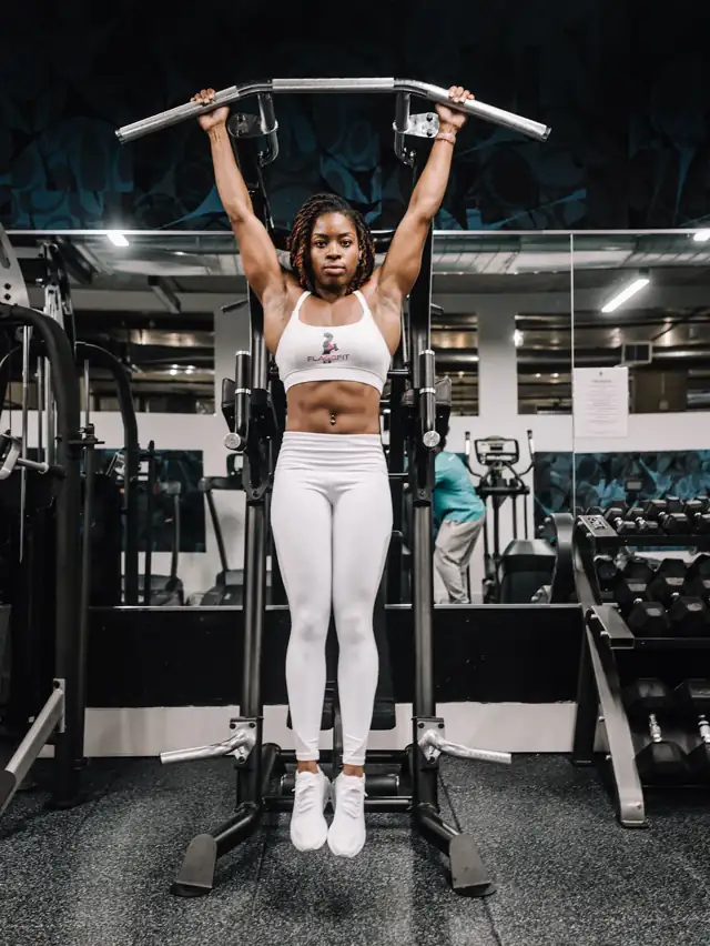 Mulher fazendo barra fixa em uma academia